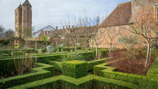 Angled hedges and winter trees with part of the castle in the background